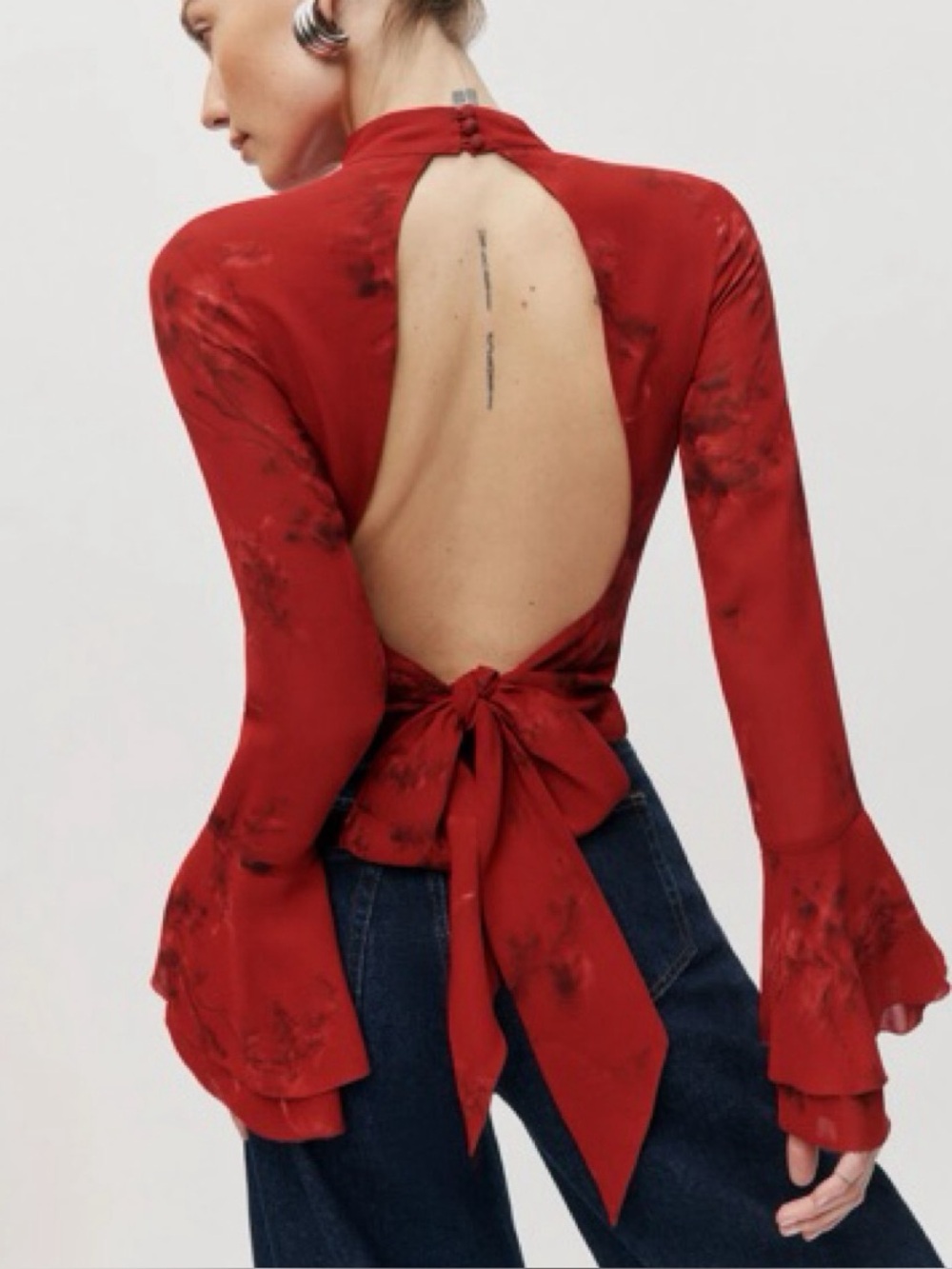 Roxana top in a vermillion red floral print, featuring a mock neck & flutter sle